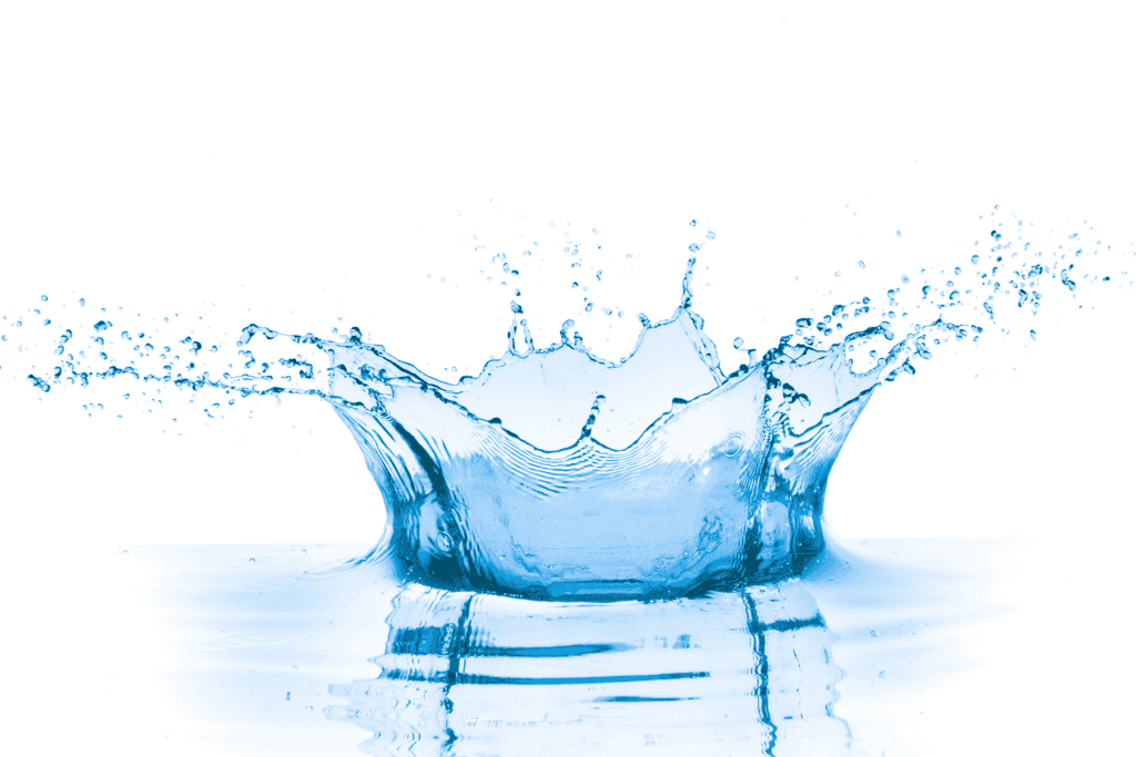 A droplet of water splashes, creating a crown-shaped ripple and water spray on a clear, reflective surface with a white background.